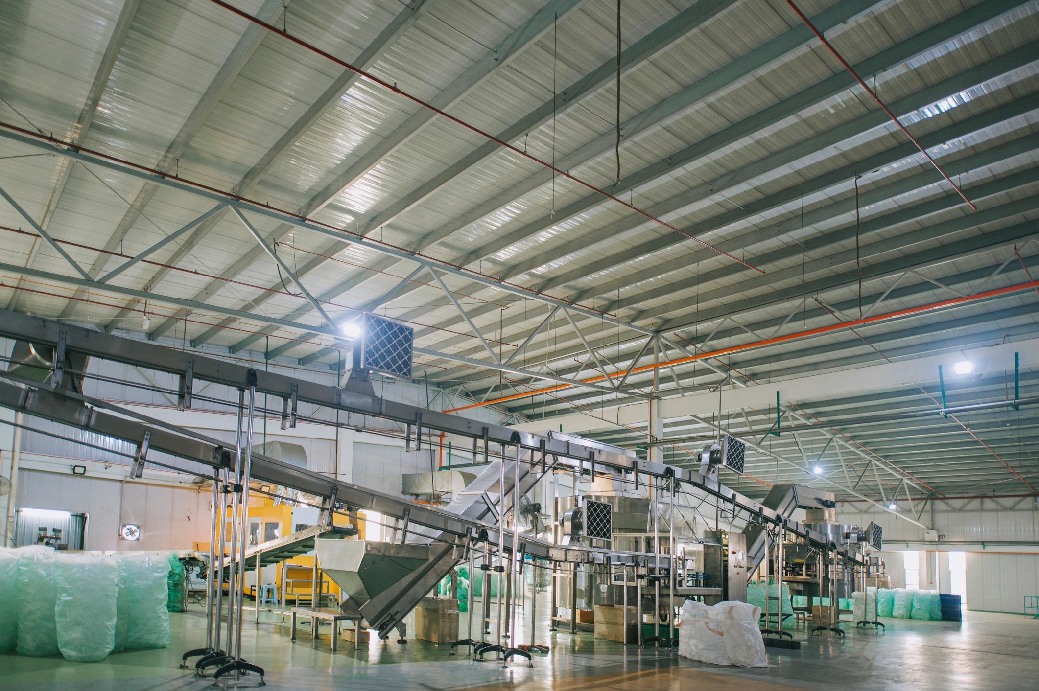 Línea de producción en planta con transportador y botellas, vista interior
