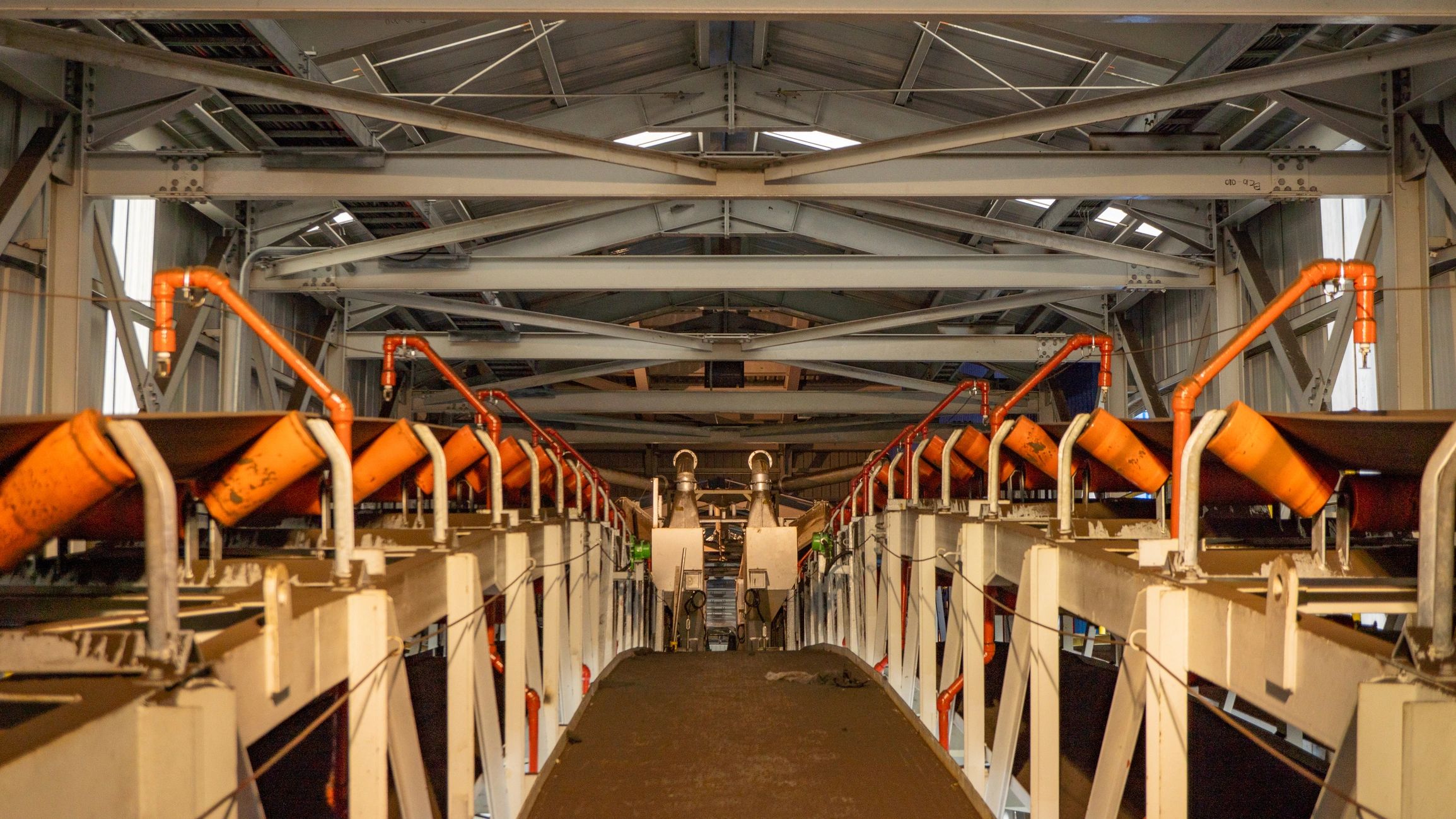 Sistema de conveyor industrial en planta, estructura metálica y banda transportadora naranja